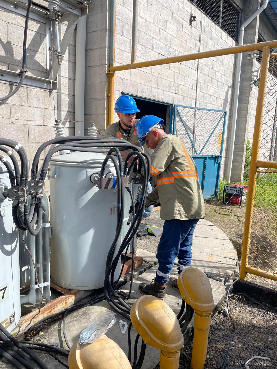 Técnicos trabajando en un transformador dentro de una instalación eléctrica